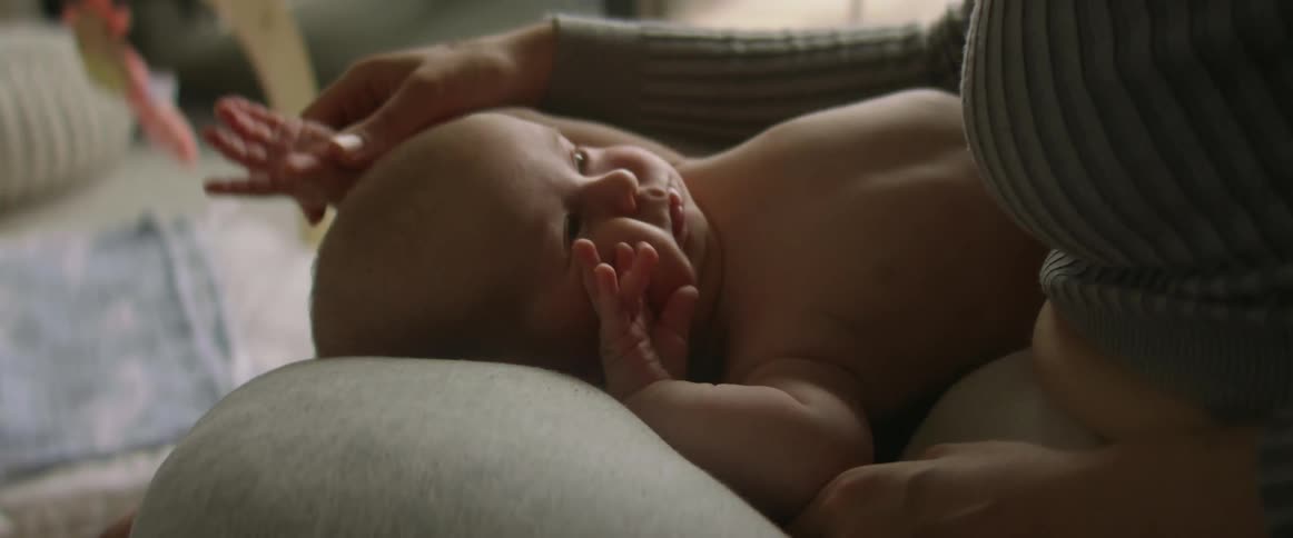 Mother sitting on couch holds baby with diaper in the living room