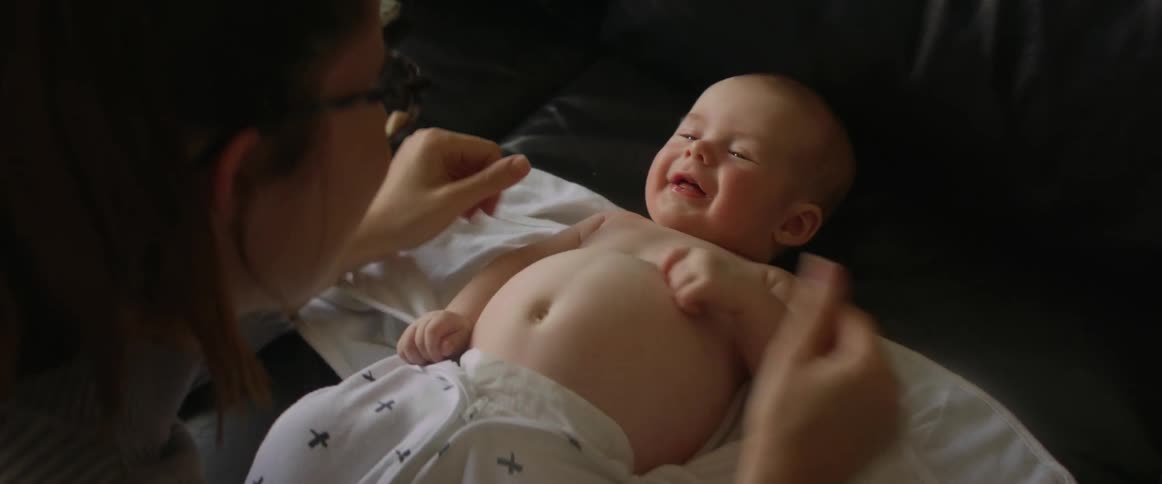 Mother plays with baby lying on couch