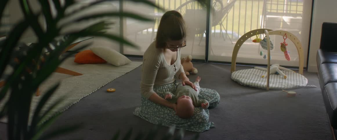 Mother kneels on living room floor with baby in her lap