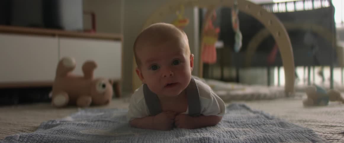 Infant looks around while laying on a blanket on the floor