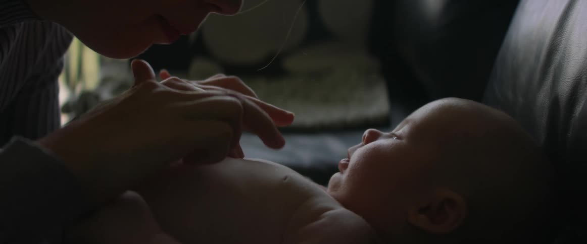 Mother ticking the belly of her newborn son at home