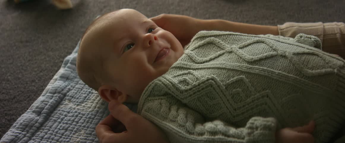Happy baby on the floor in a baby sweater