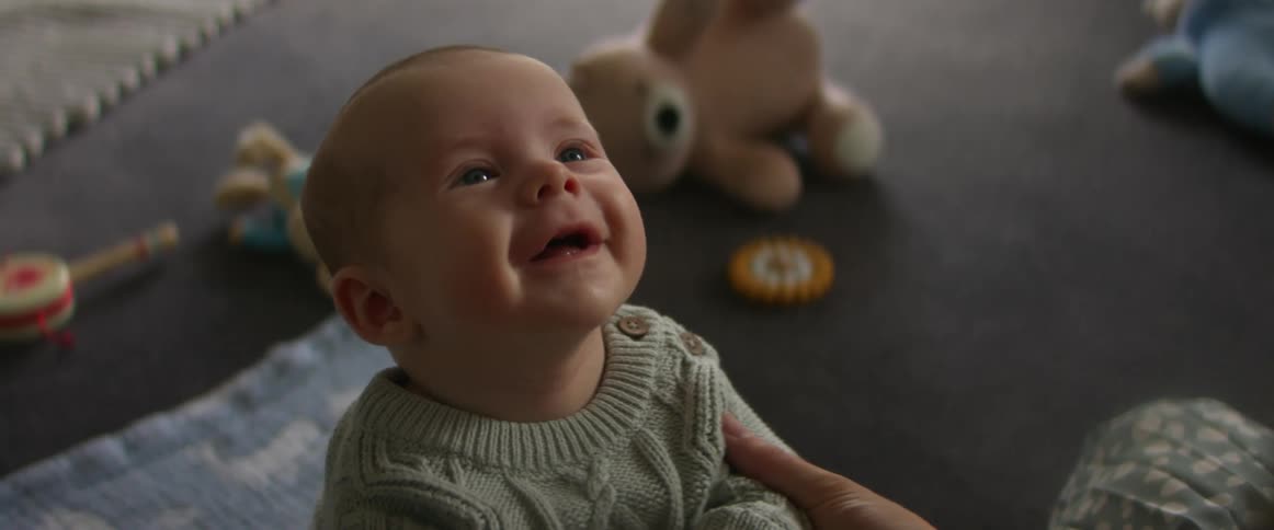 Baby son looks up at his mother smiling broadly