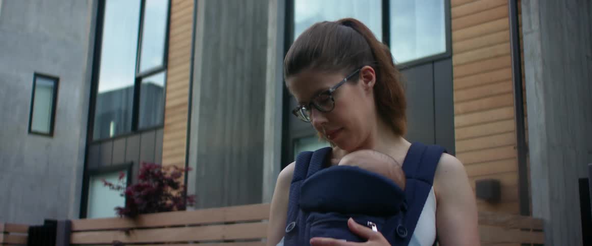 A mother is holding her baby outside by the home