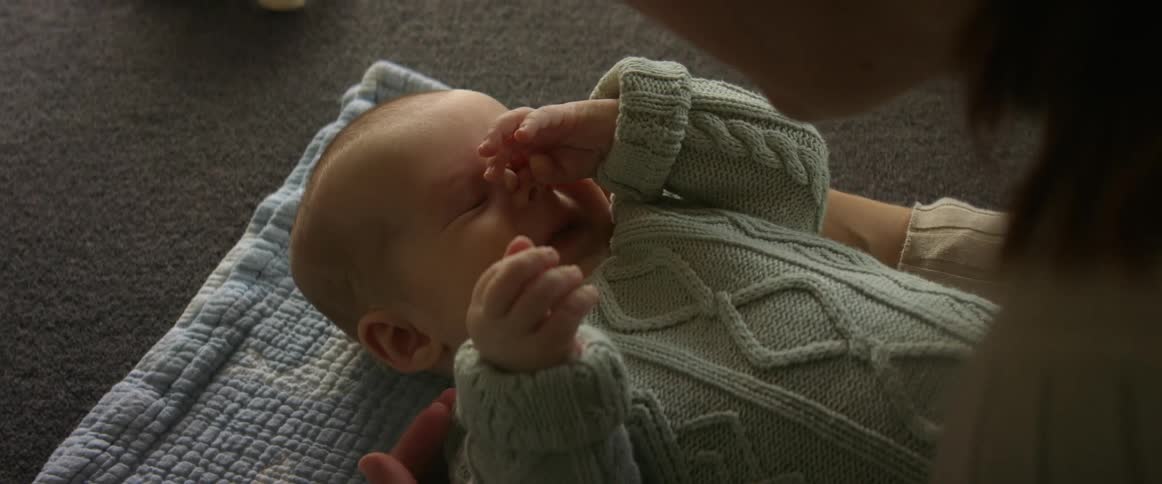 Mom engaging with infant on blanket baby coos and smiles at mom
