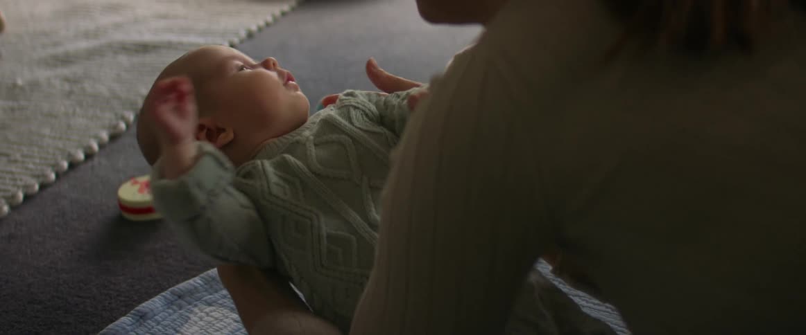 A woman holds up a baby in her arms while the baby squirms