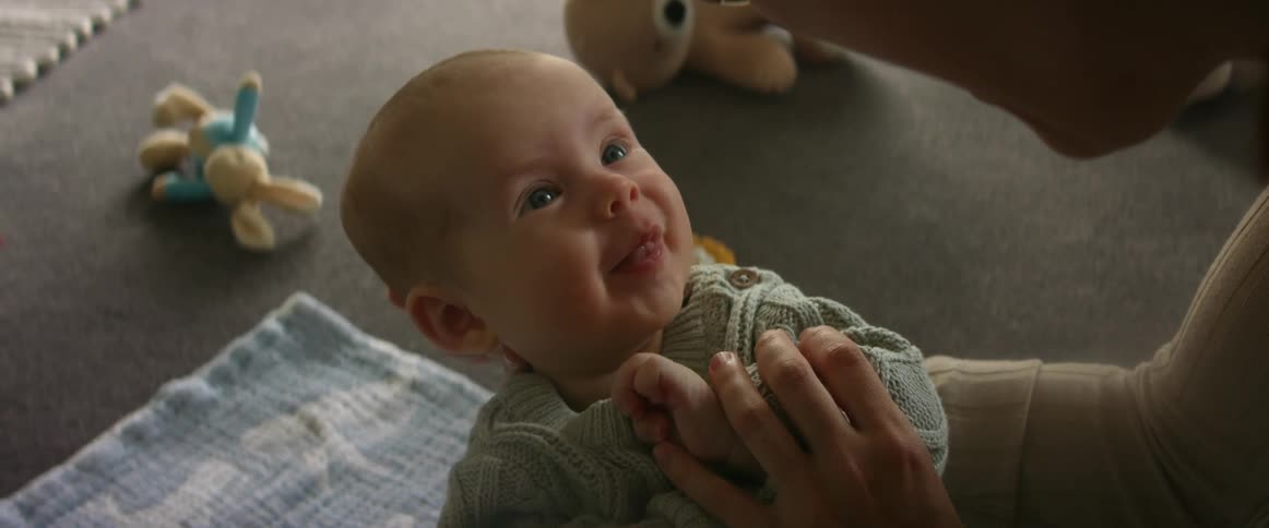 A mother is cradling her baby boy while he stares up at her and smiles