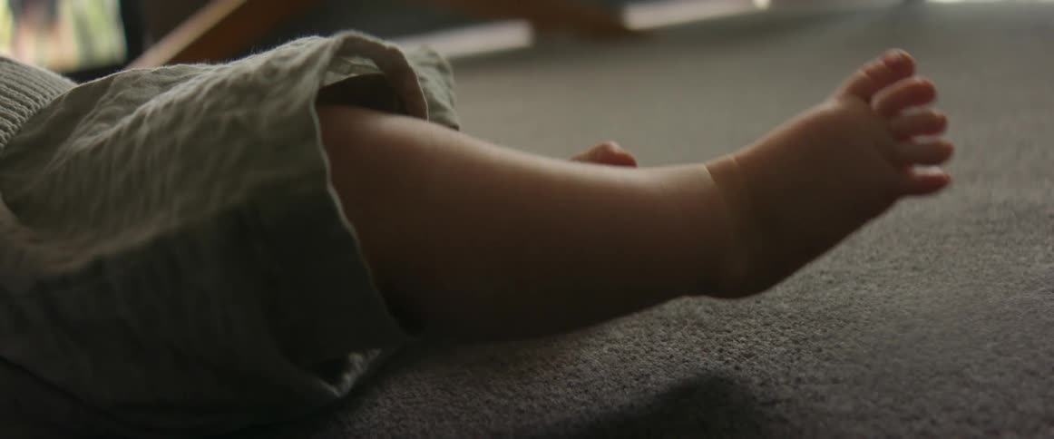 Baby kicks foot while lying on carpeted floor