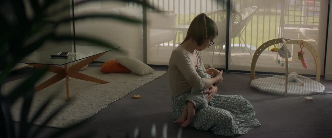 Mother sitting on living room floor breastfeeding baby