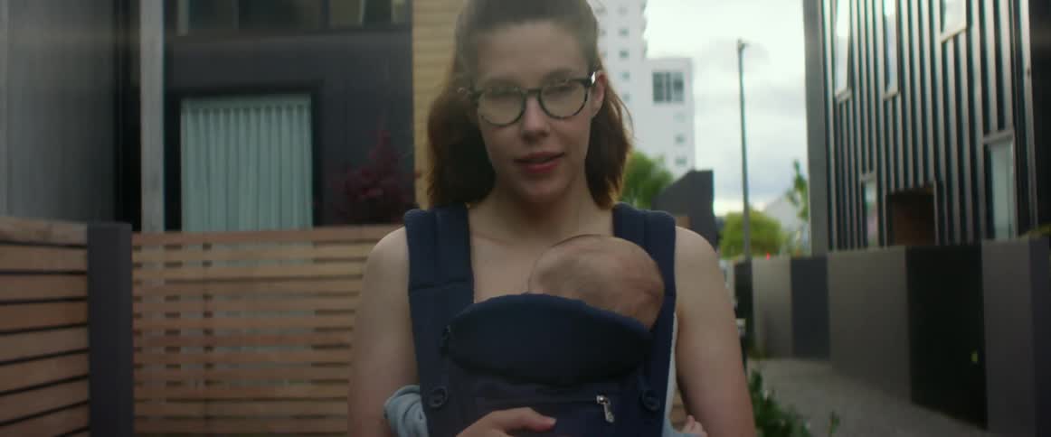 Mother carrying baby and walking down sidewalk in residential area