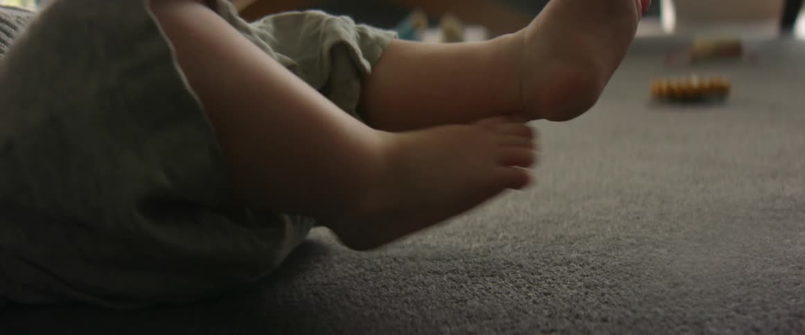 Close up of the kicking feet of a baby laying on the carpet at home