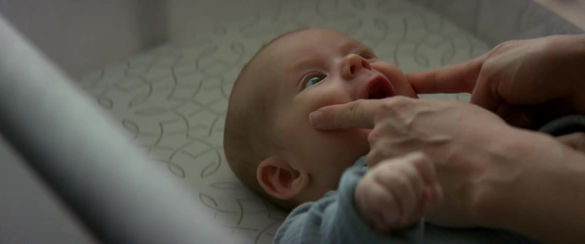 A mother pokes at her babies cheeks making him laugh and smile