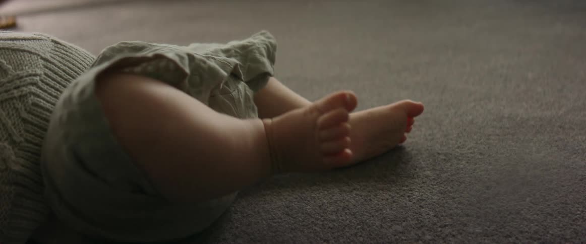 Infant baby lying on carpet kicking legs and wiggling feet
