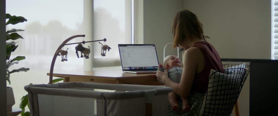 A woman sitting at a desk holding a baby