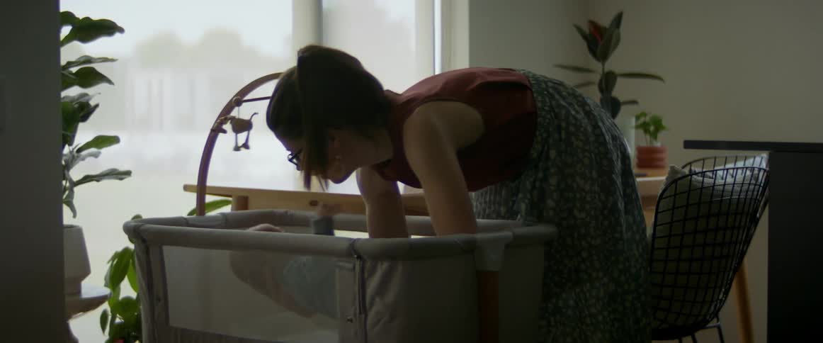 A mother picking up her baby out of the crib