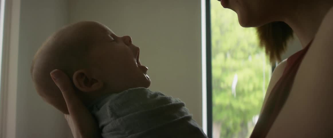A woman holds her baby and smiles at him as he coos