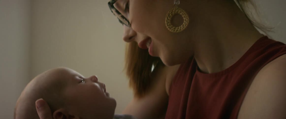A mother holds her baby face to face smiling at him