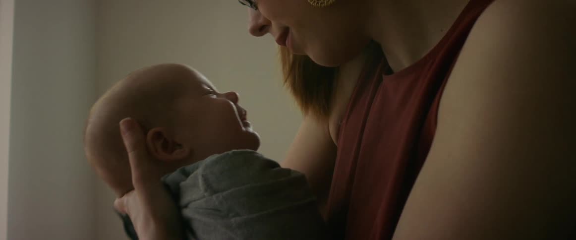 A woman holding her baby kisses her forehead and they make faces at each other