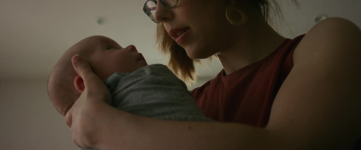 Mom standing while rocking sleeping infant in bedroom