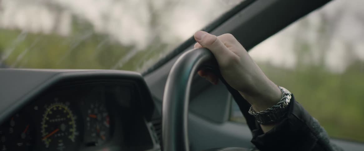 Woman steers car past countryside during a road trip