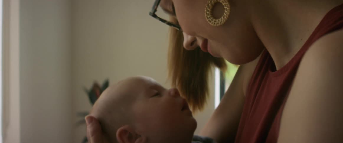 A close up of a mother holding a baby in her arms swaying back and forth