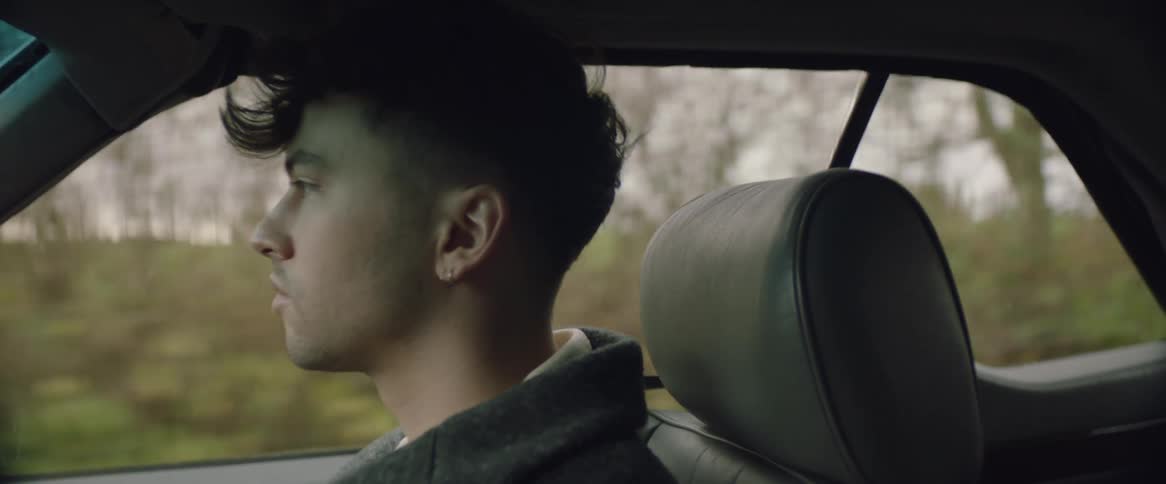 An up close of a mans head and face as he drives a car