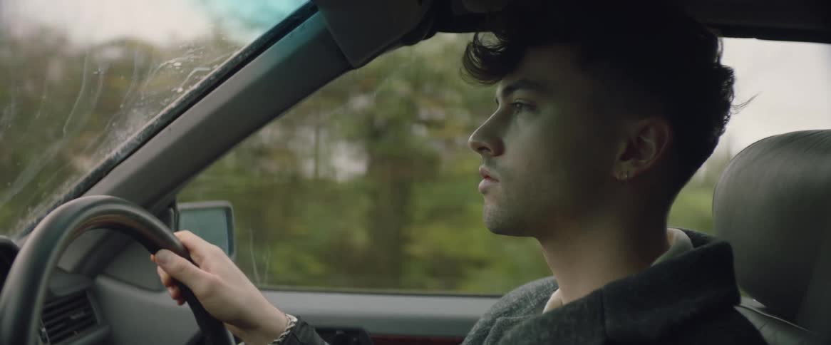 A man is talking to himself as he drives an automobile on a country road