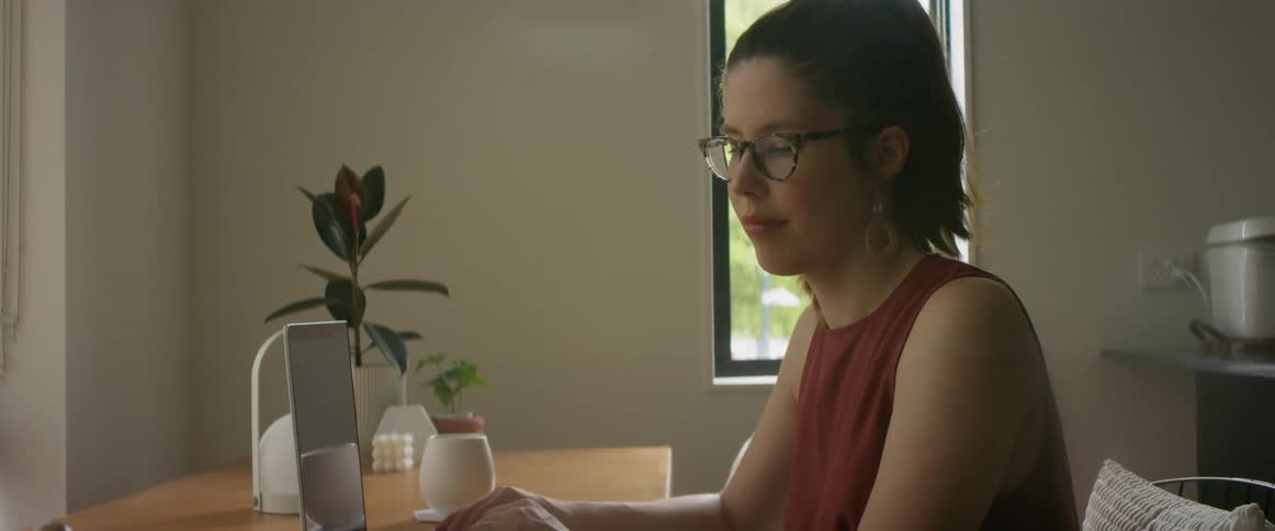 Woman working at home leans over to touch her baby