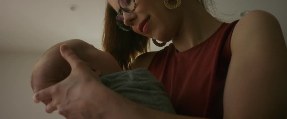 A mother cradles her sleeping newborn baby