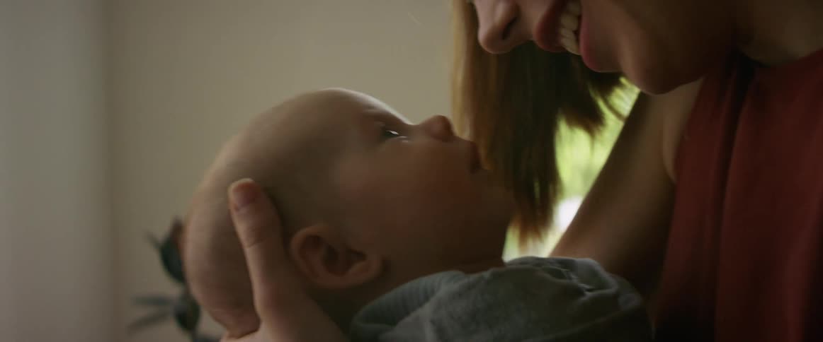 A woman holds her baby and rocks him and smiles down at him