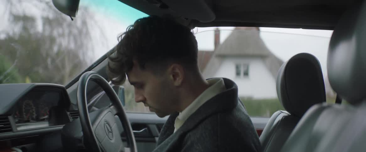 A young man gets into a car thats parked in a residential neighborhood