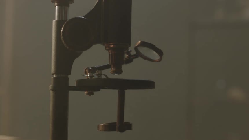 An old style microscope sits in a sunlight lab