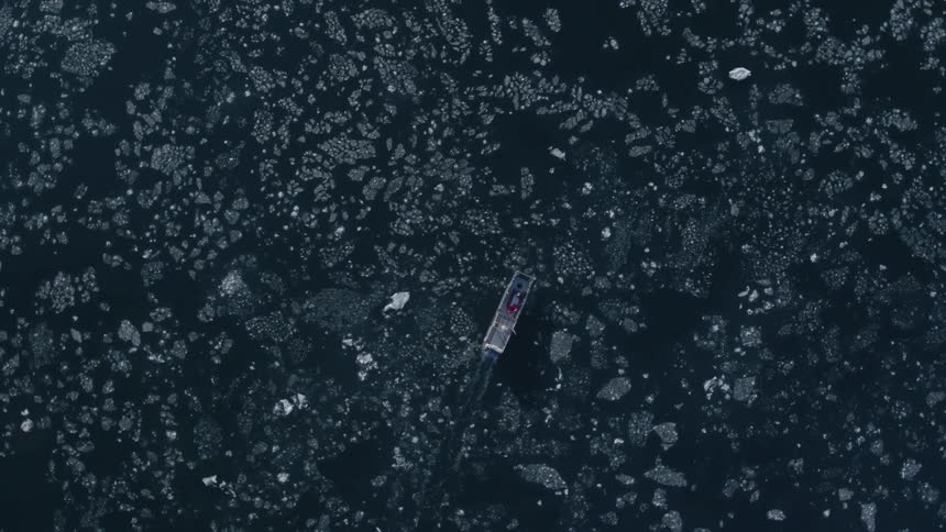 A boat sails in the ice below