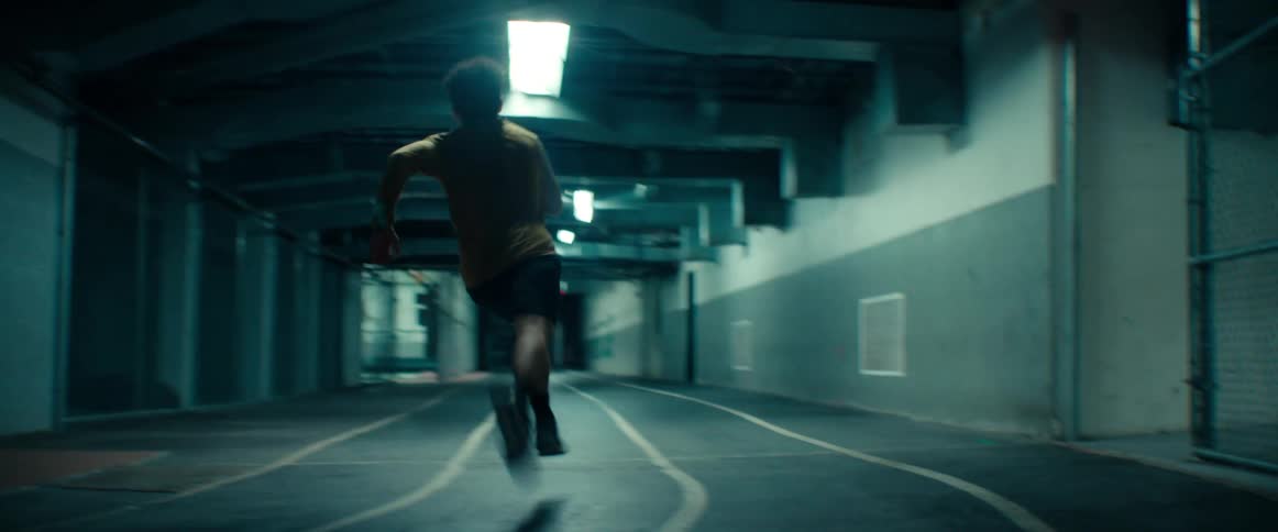 A man running on an indoor track running around a corner