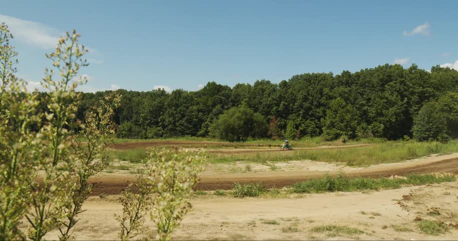 A person riding a dirt bike through a dirt track in an open field