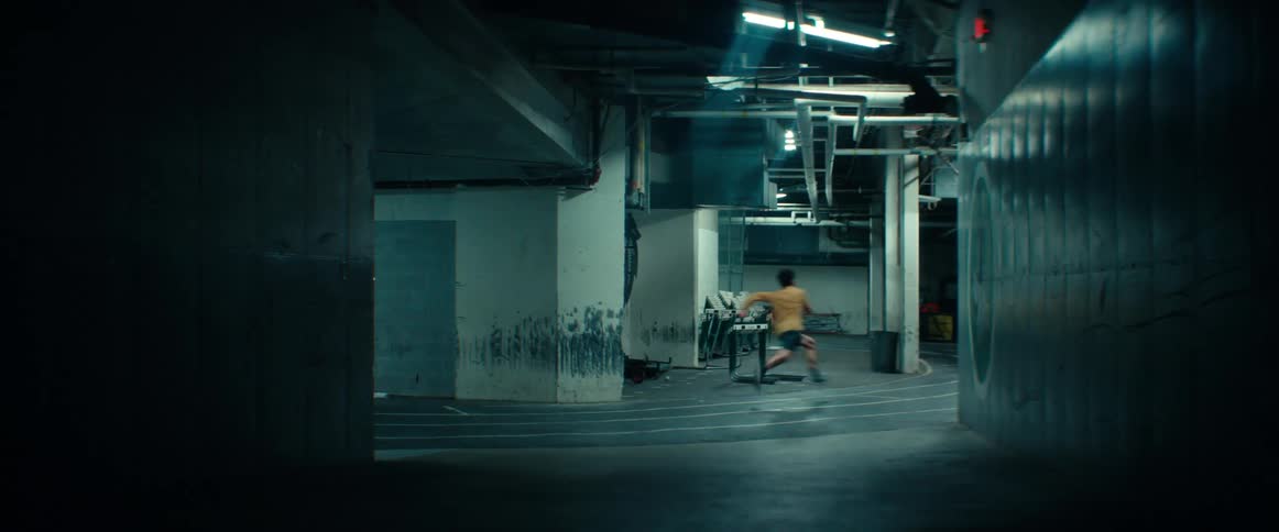 A teenage boy is running around an indoor track