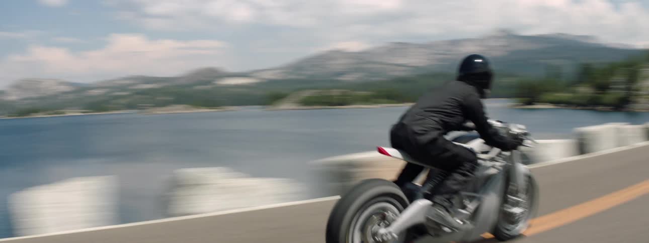 A person rides over the bridge on a motorcycle