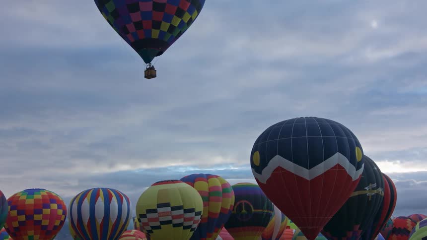 Several hot air balloons are lifting off the ground in a sped up video