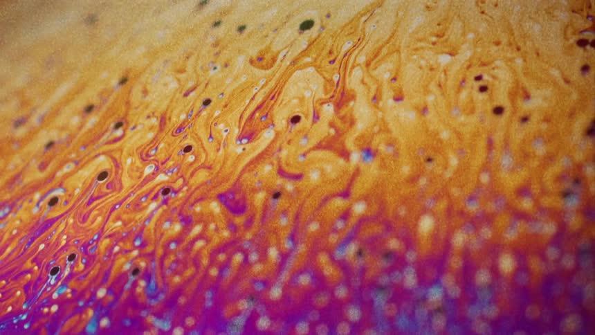 Colorful liquids swirl and blend together in a container