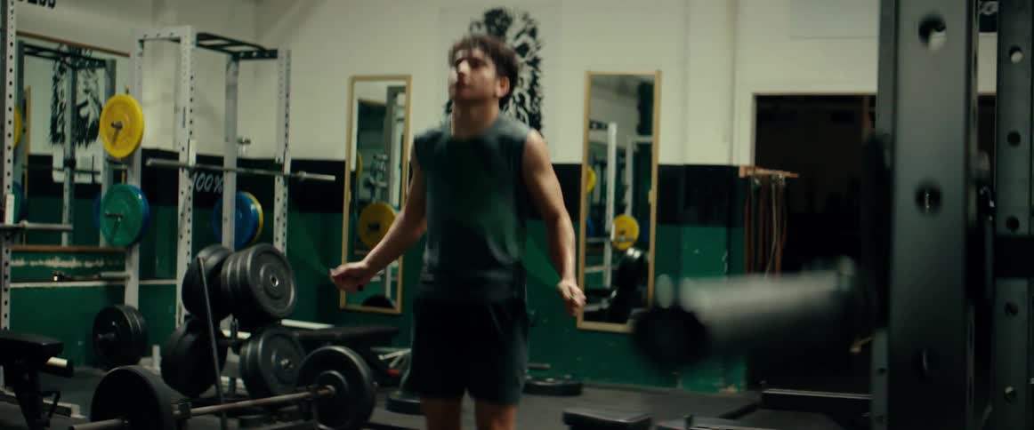 Muscular man with shirt and shorts jumps rope in the gym