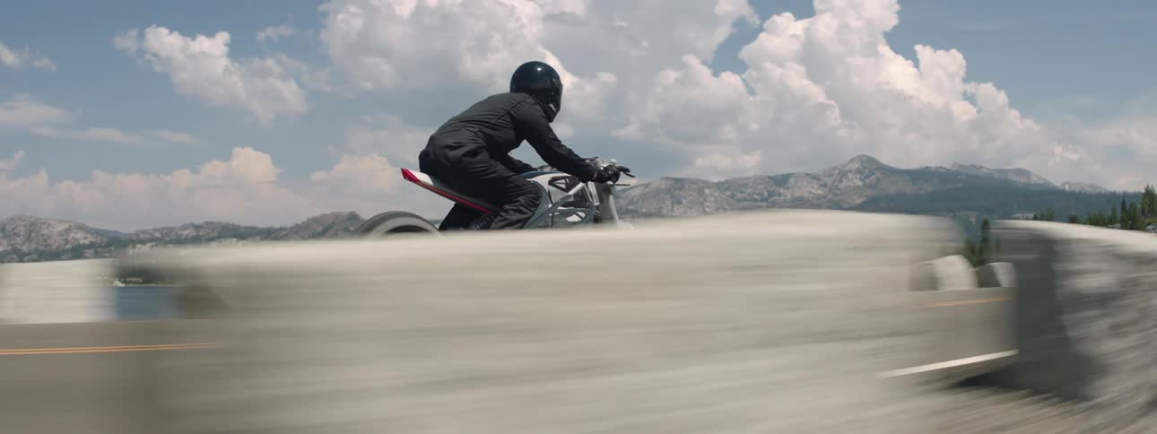 Motorcycle driving on a road next to a lake at daytime