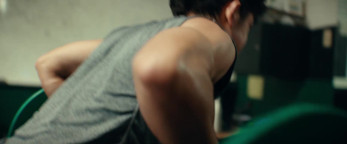 A young man makes a strained expression while weightlifting in a gym