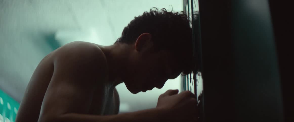 An up clsoe of a man leaning his head against lockers angrily yelling