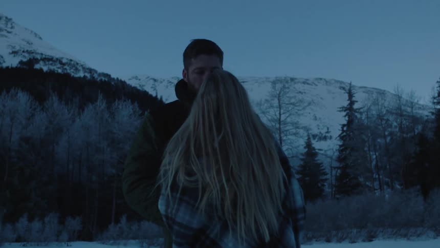 A man and woman stand close together at dawn