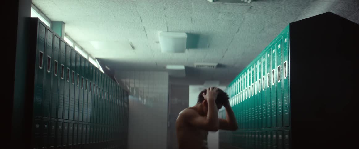 A sweaty man walks around the locker room