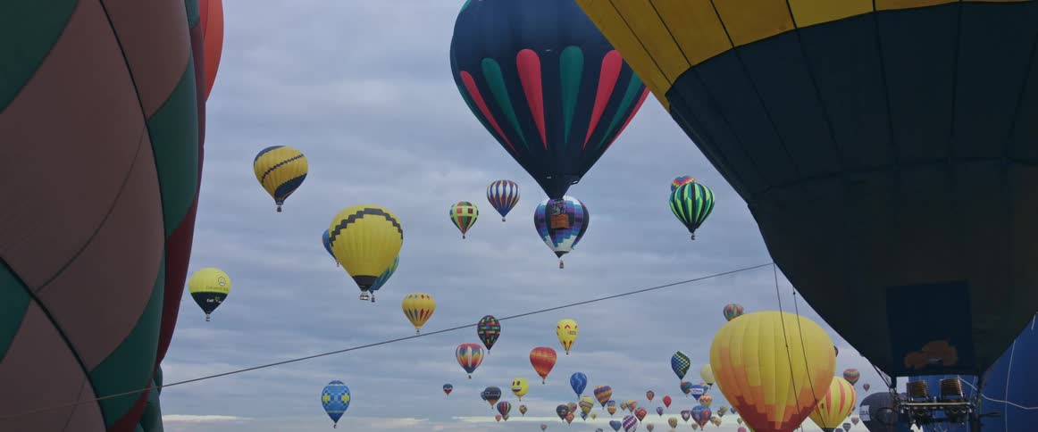 Colorful hot air balloons float in a cloudy sky