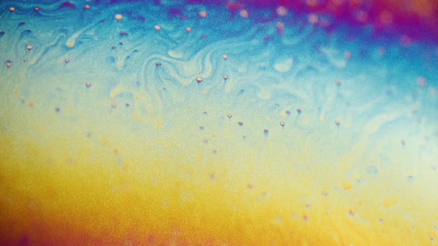 Fluorescent colors move and streaks blend as small particles float over the surface colors as they stretch