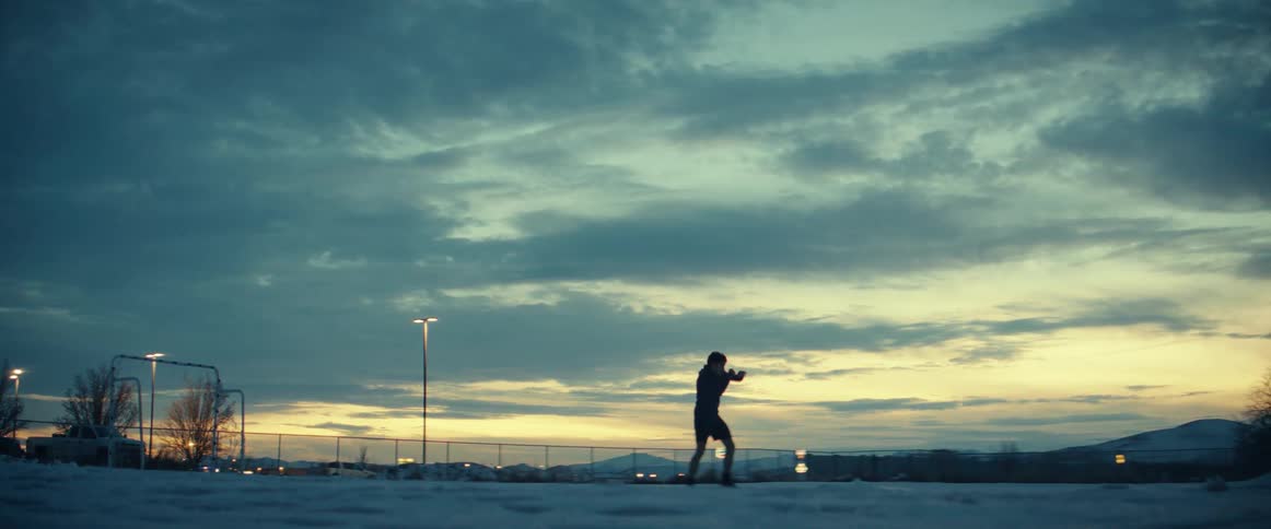 Man shadowboxing in silhouette at dawn in an open field