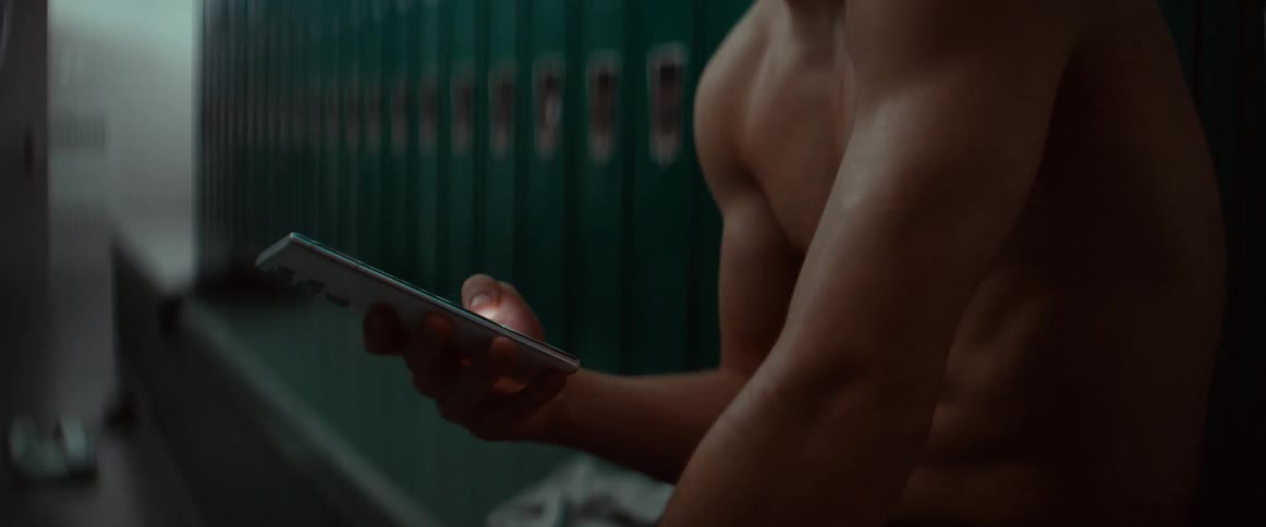 A teenager is using a cell phone in the locker room