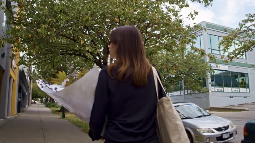 A woman walking down a sidewalk with a bouquet in her hands